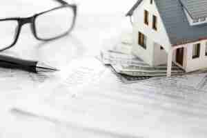 miniature model house on top of cash and papers