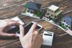 Person calculating property value with miniature model homes
